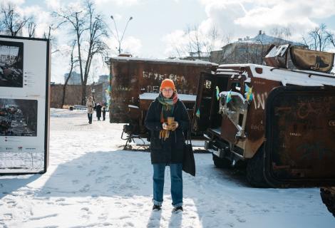 Olena, a Ukranian humanitarian worker poses in front of a snowy industrial background in Kharkiv